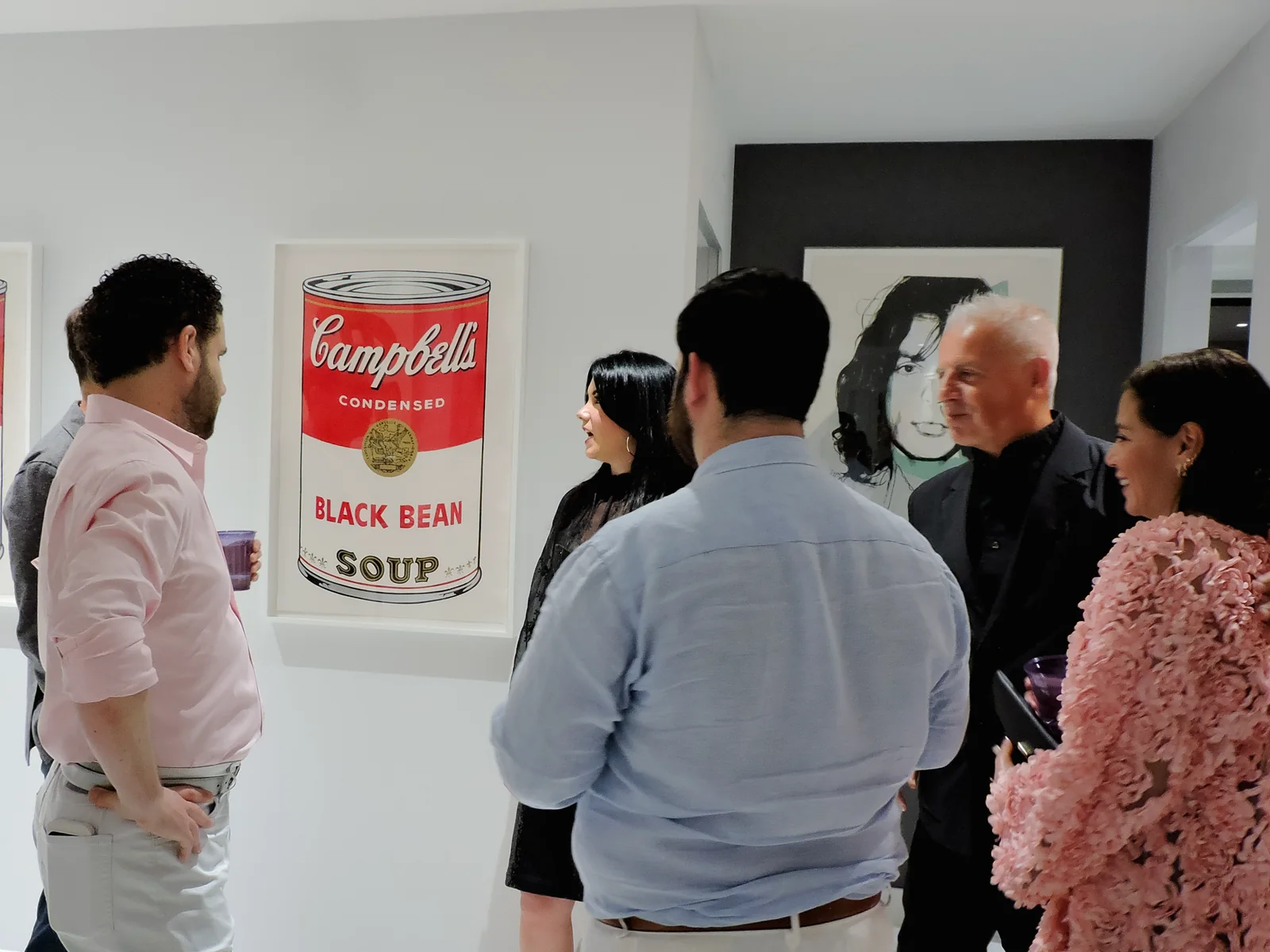 Guests talking in front of a framed Andy Warhol Campbell’s Black Bean Soup print