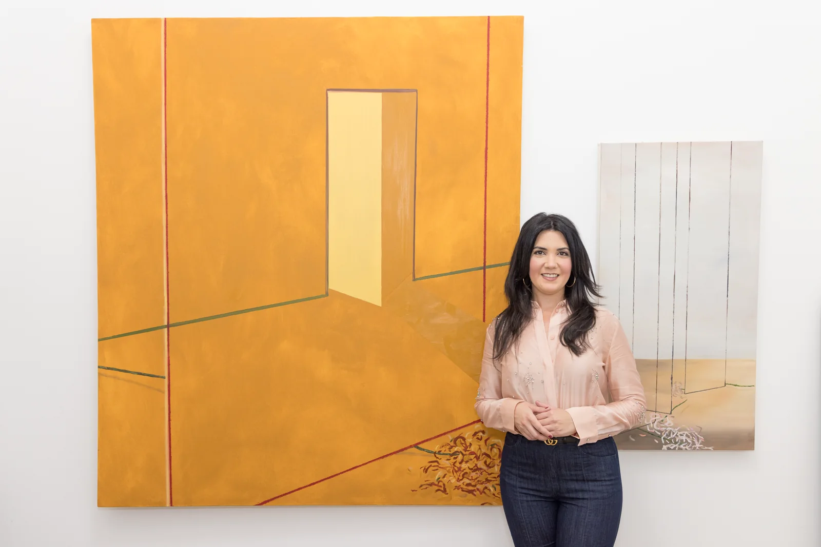 Jennifer Victor standing beside a large ochre painting