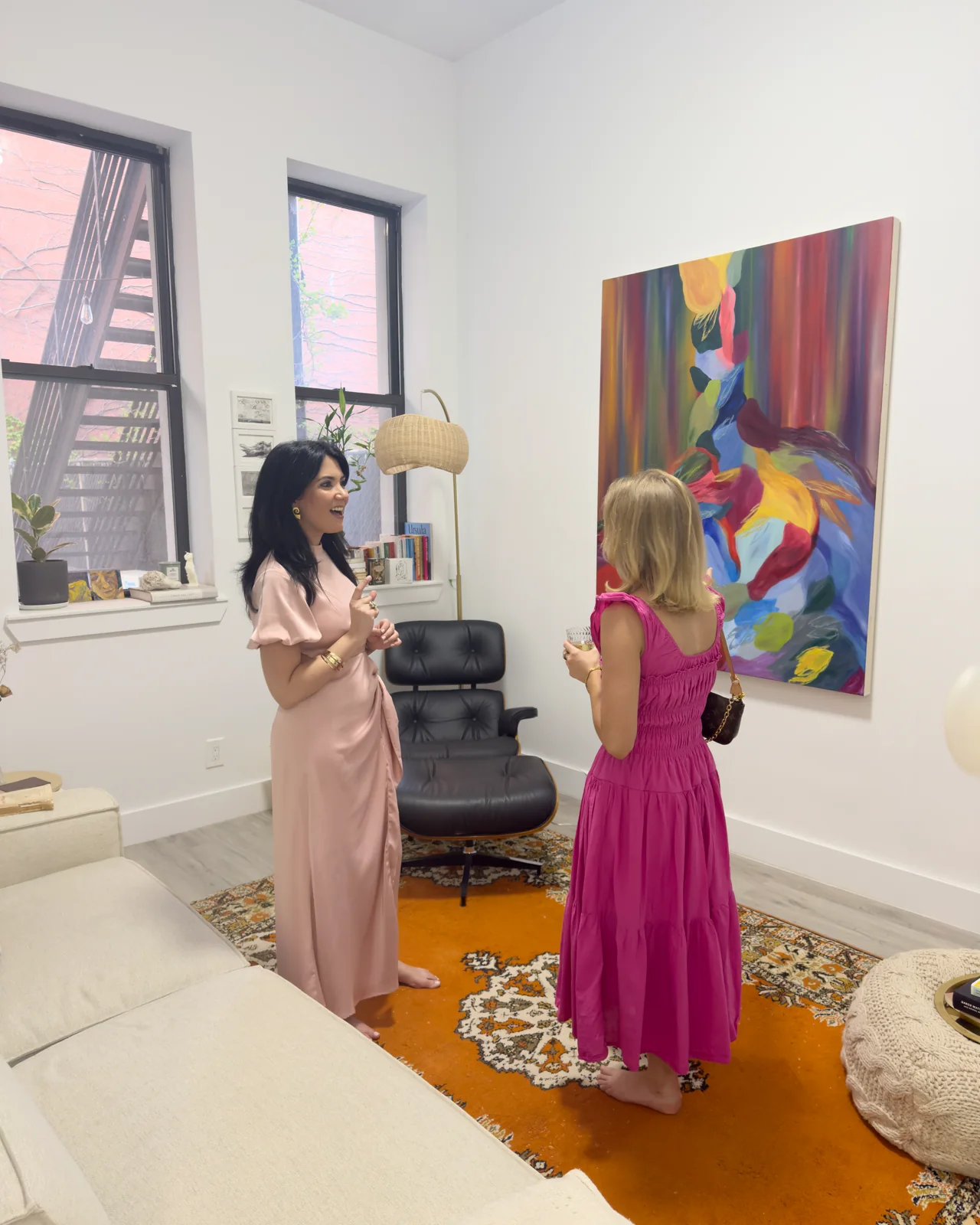Two people in conversation beside a large abstract painting in a living room